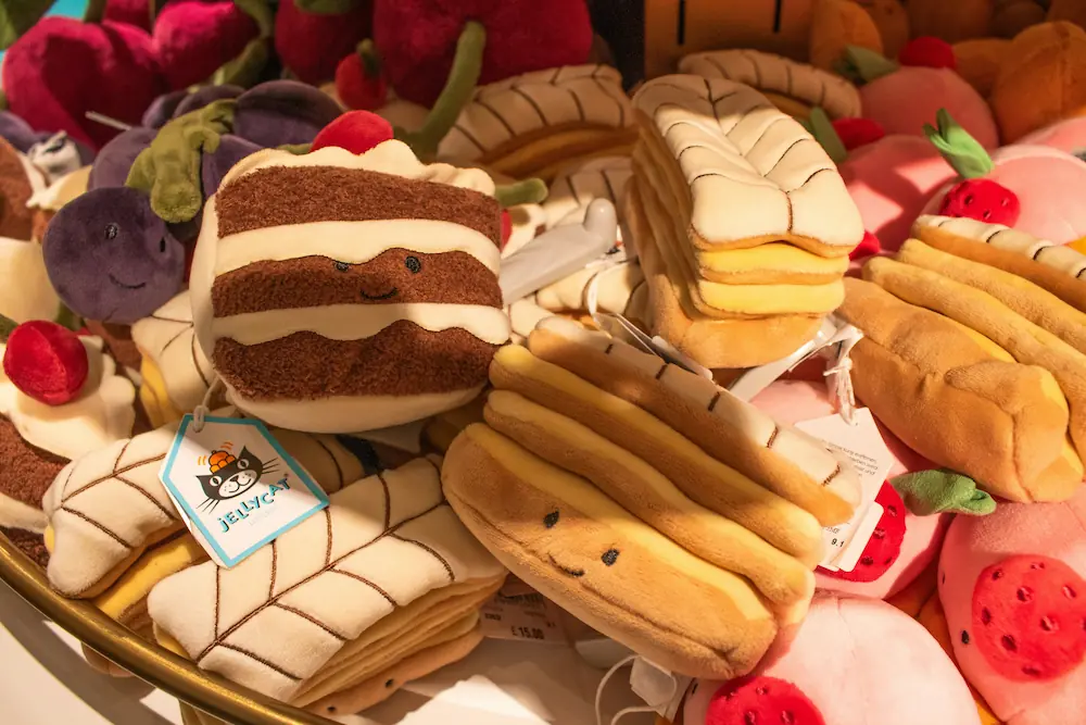 Een verzameling Jellycat pluchen speelgoed in de vorm van verschillende gebakjes en vruchten.